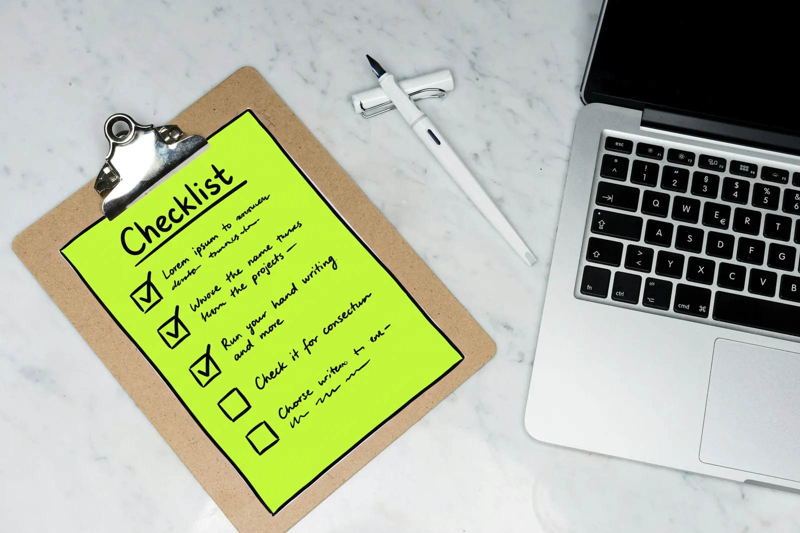 An onboarding checklist on a clipboard beside a laptop, the checklist drawn in lime ink